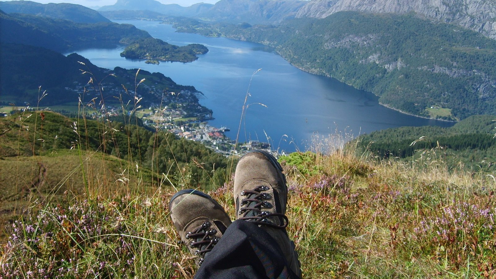 Hiking boots resting in the heather above a Norwegian fjord