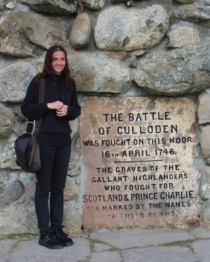 Angélique Olivia standing by the Culloden cairn plaque: “The Battle of Culloden was fought on this moor, 16th April 1746”