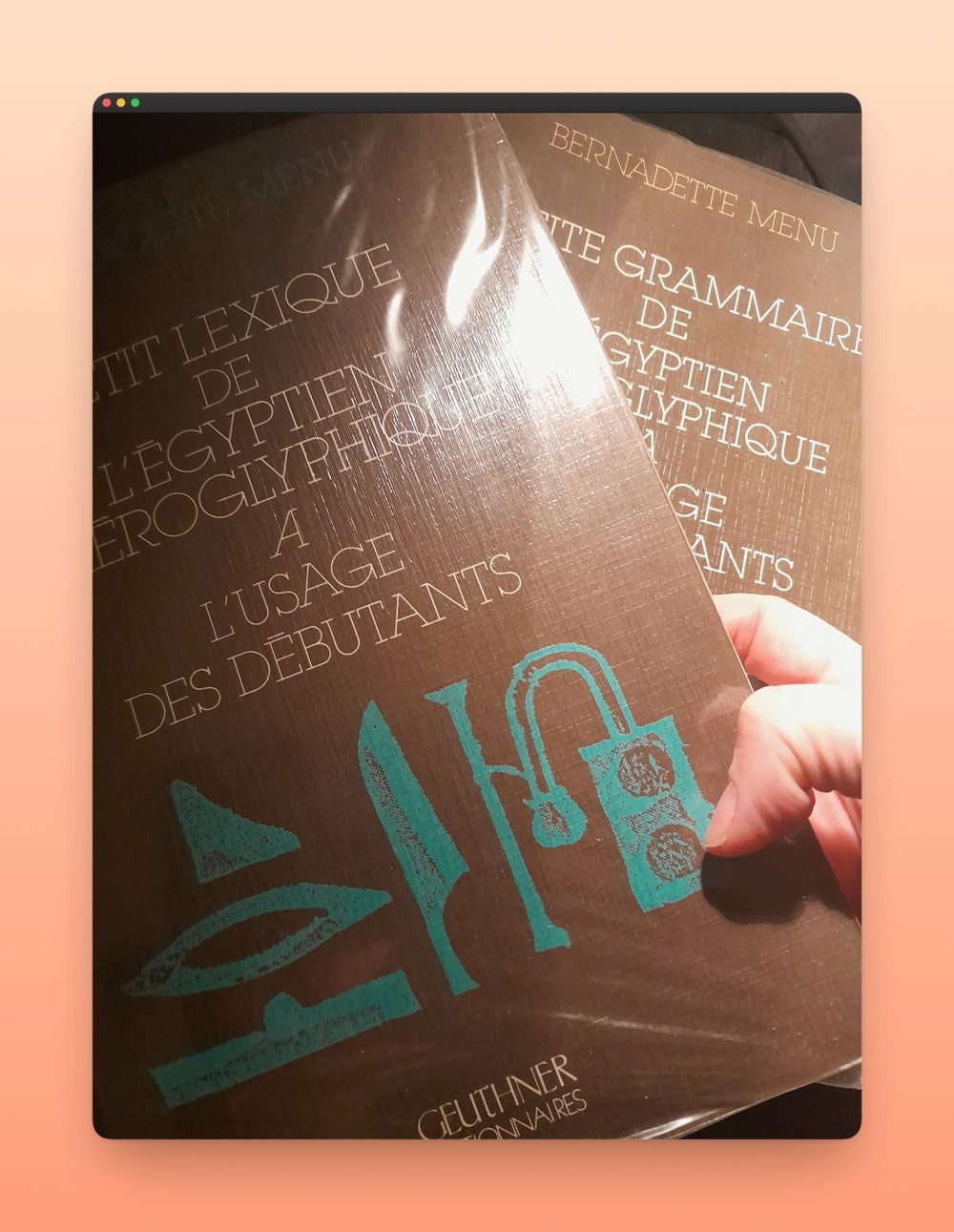 Angélique Olivia’s hand holding her two Ancient Egyptian course books by Bernadette Menu